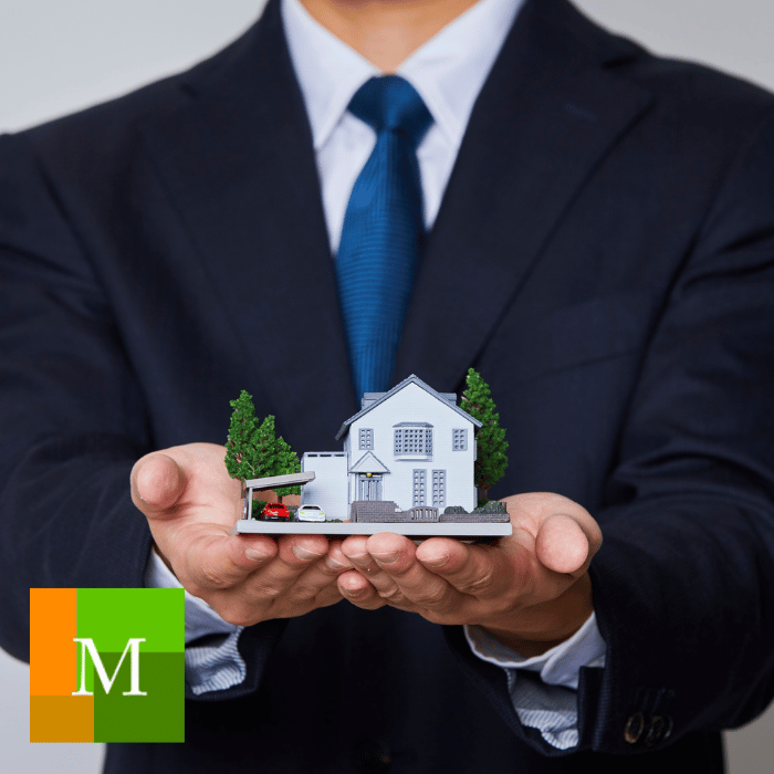 Property manager holding a model home in open hands, symbolizing care and protection